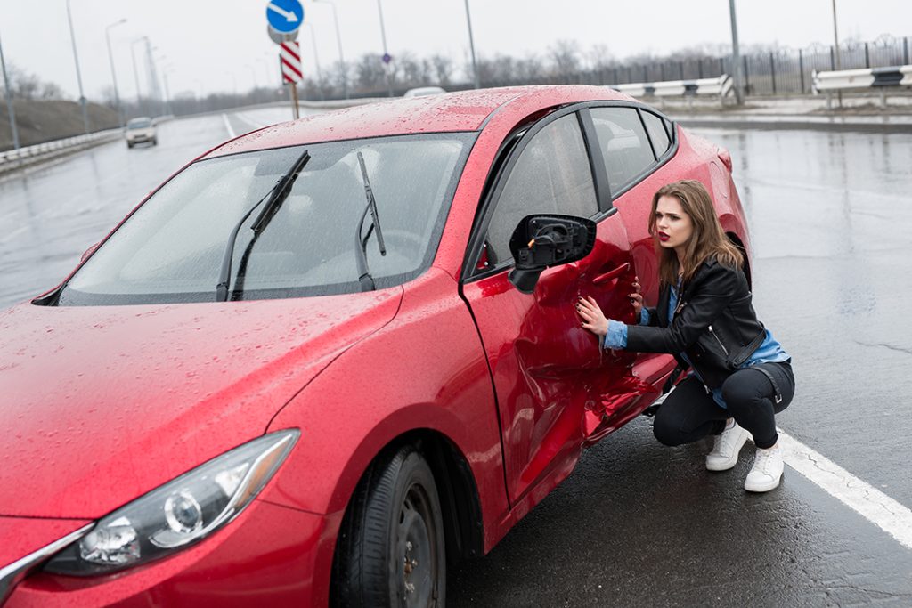 Home 15 woman sits near a broken car after an accident ca 2025 04 22 16 20 22 utc